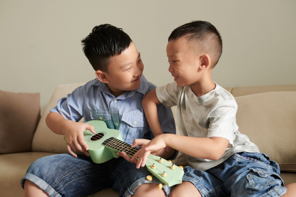 Cheerful boys play with a ukelele.