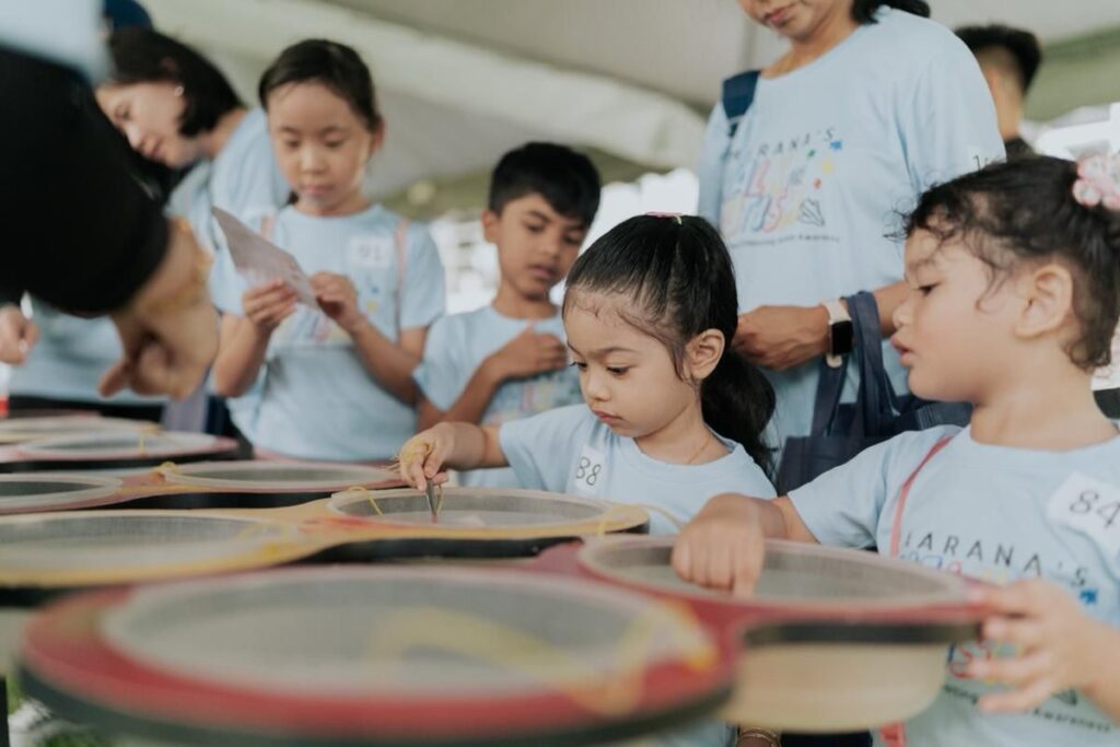 Children participating in hands on activity during walk for autism, guided by adults 