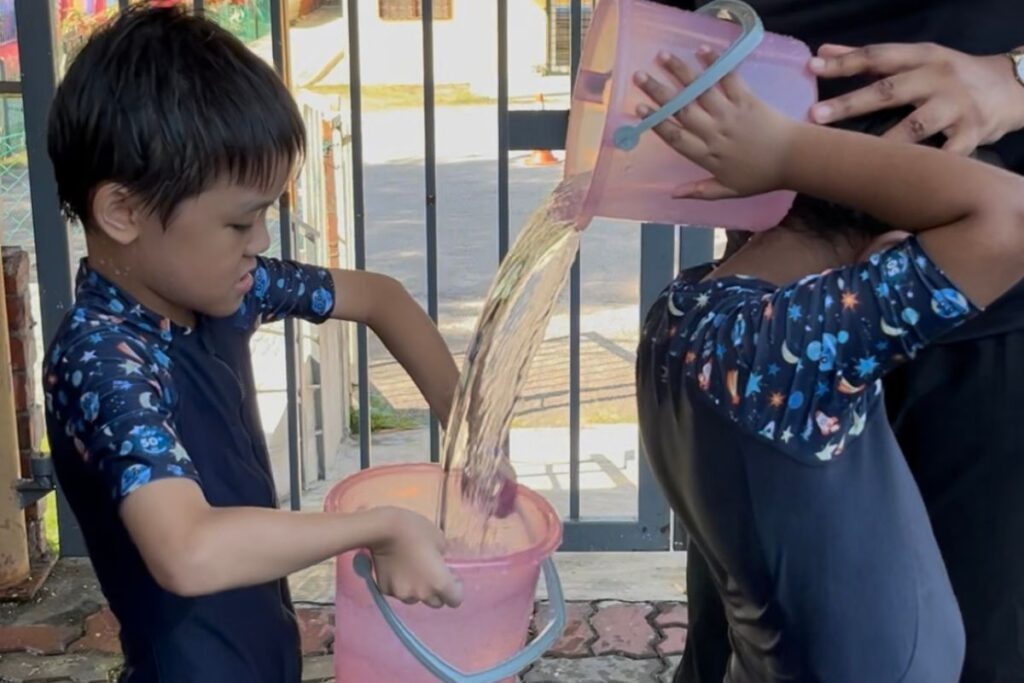 Kids pouring water inside a bucket